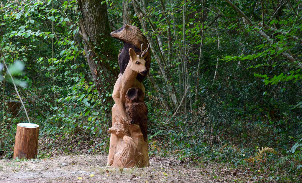 totem d'animaux sculptés en bois à la tronçonneuse pour un sentier d'interprétation en forêt